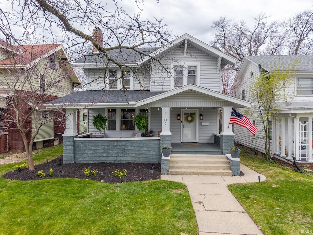 view of front of home featuring a porch, a front lawn, and a chimney