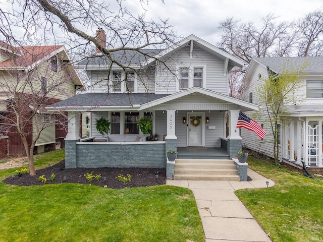 view of front of home featuring a porch, a front lawn, and a chimney