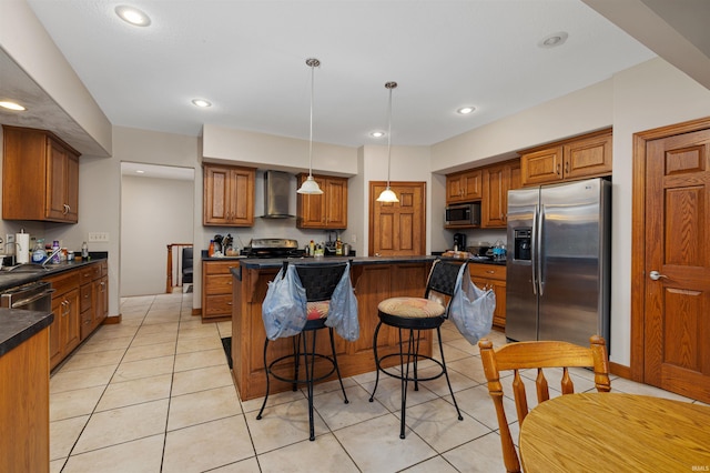 kitchen with wall chimney range hood, a center island, dark countertops, brown cabinets, and appliances with stainless steel finishes