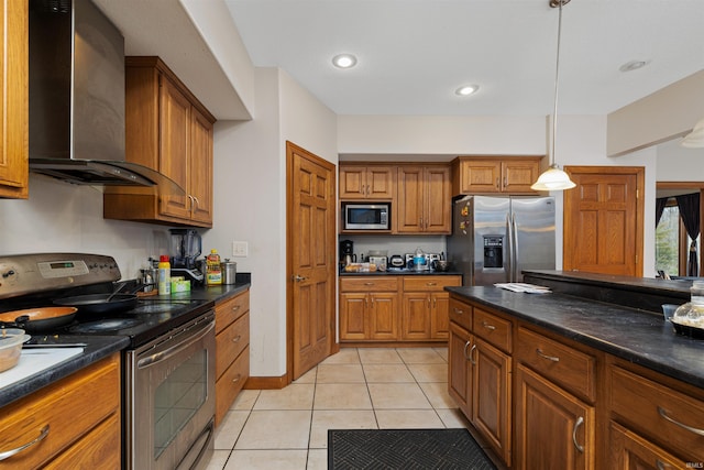 kitchen featuring brown cabinets, dark countertops, wall chimney range hood, and appliances with stainless steel finishes