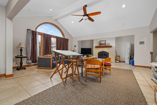 dining space with a ceiling fan, light tile patterned floors, beam ceiling, baseboards, and a glass covered fireplace