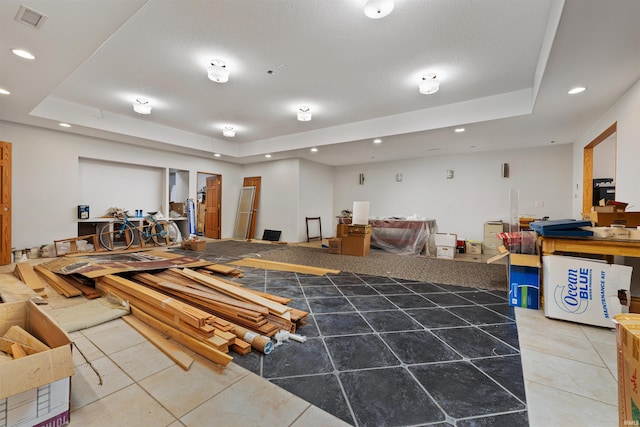 misc room with light tile patterned flooring, a tray ceiling, and visible vents