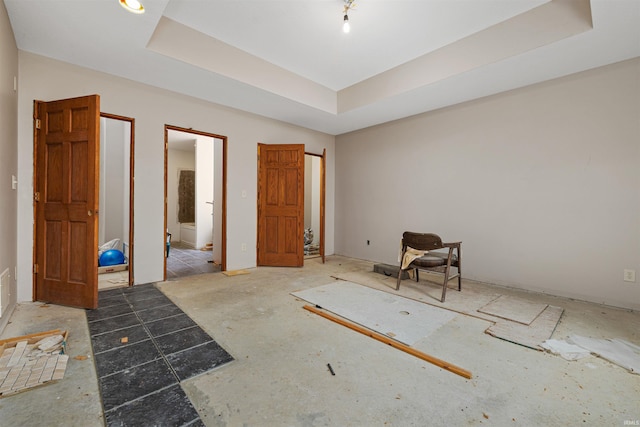 unfurnished bedroom featuring a tray ceiling and ensuite bathroom