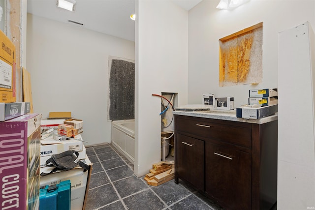 bathroom with tile patterned flooring, vanity, visible vents, and a bathing tub
