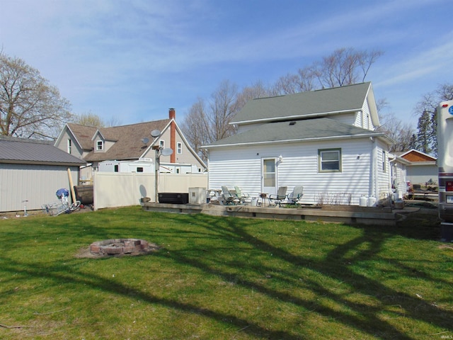 back of property with a lawn, an outdoor fire pit, and a deck
