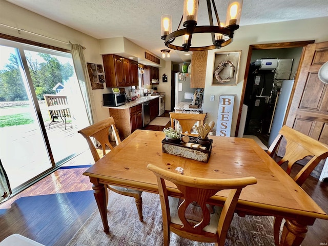 dining room with light wood-type flooring, a textured ceiling, and a notable chandelier