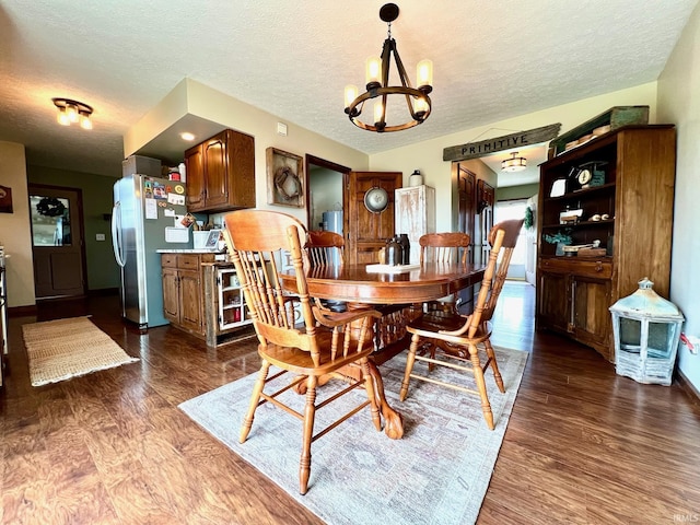 dining area featuring dark wood finished floors, a chandelier, and a textured ceiling