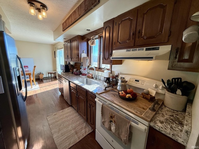 kitchen featuring exhaust hood, a sink, dark wood-type flooring, a textured ceiling, and appliances with stainless steel finishes