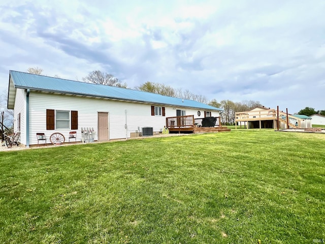 rear view of house featuring cooling unit, a lawn, metal roof, and a deck