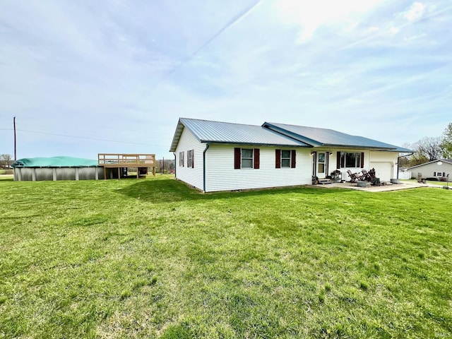 rear view of property featuring a garage, a lawn, and metal roof