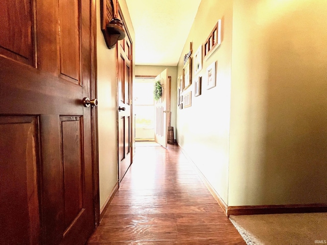 corridor featuring baseboards and wood finished floors