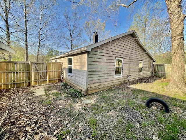 view of home's exterior featuring a chimney, a gate, and a fenced backyard