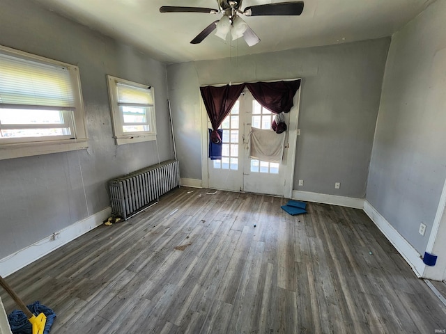 spare room with a ceiling fan, baseboards, radiator heating unit, and wood finished floors