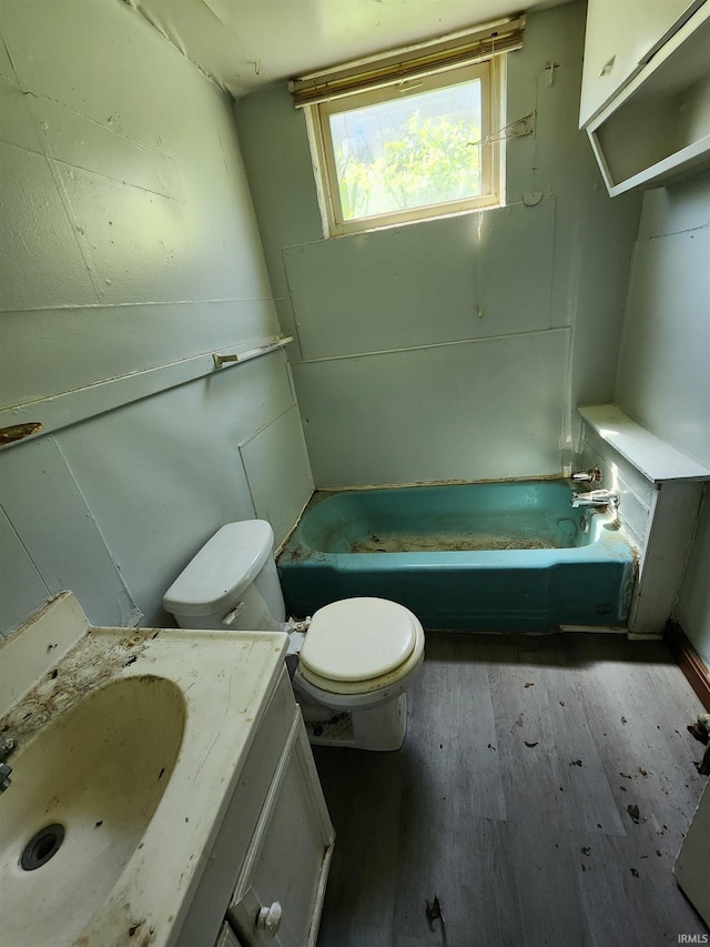 full bathroom featuring a washtub, toilet, vanity, and wood finished floors