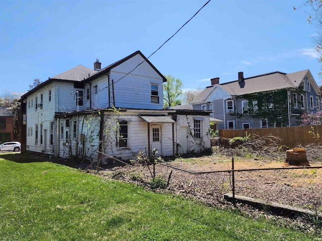 rear view of property with a yard and fence