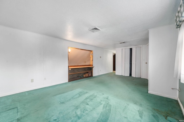 unfurnished living room with baseboards, carpet flooring, a textured ceiling, and visible vents