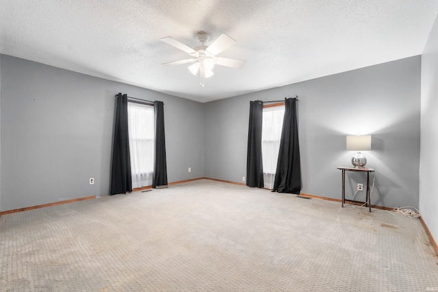 spare room with carpet flooring, a textured ceiling, ceiling fan, and a healthy amount of sunlight