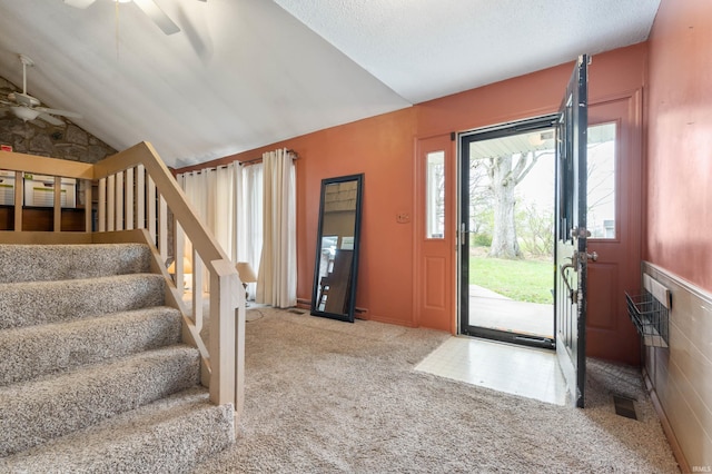 carpeted foyer featuring stairway, vaulted ceiling, and a ceiling fan