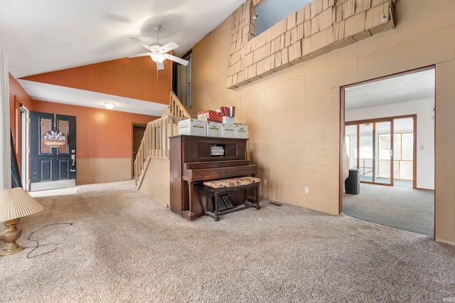 living area with lofted ceiling, a ceiling fan, stairs, and carpet