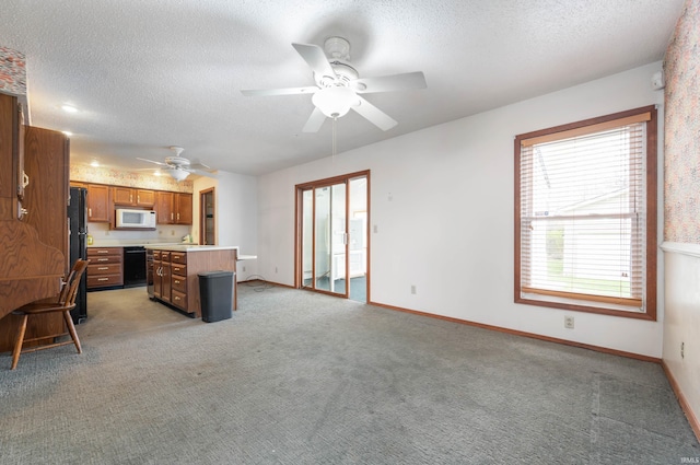 unfurnished living room with a textured ceiling, a ceiling fan, baseboards, and light carpet