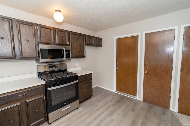 4829 Kintyre Dr, South Bend, IN 46614 - kitchen featuring a textured ceiling, dark brown cabinetry, light wood-style floors, light countertops, and appliances with stainless steel finishes