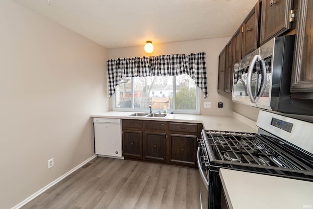 4829 Kintyre Dr, South Bend, IN 46614 - kitchen with light countertops, a sink, light wood-style floors, dark brown cabinetry, and appliances with stainless steel finishes
