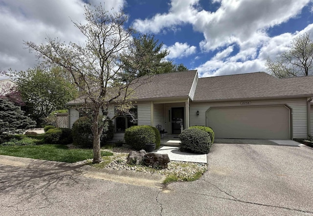 single story home featuring aphalt driveway, roof with shingles, and a garage