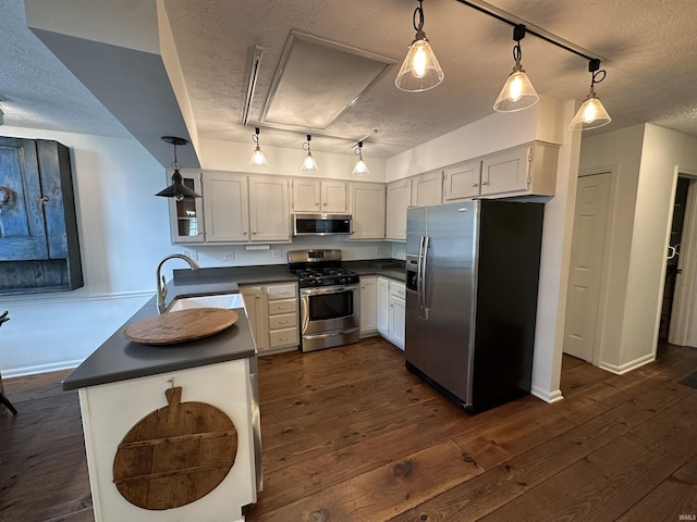 kitchen with stainless steel appliances, a textured ceiling, a sink, dark countertops, and rail lighting