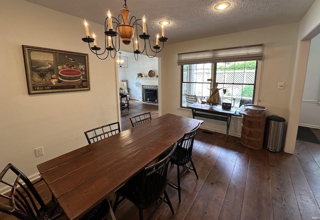 dining space featuring a textured ceiling, baseboards, an inviting chandelier, hardwood / wood-style floors, and a fireplace