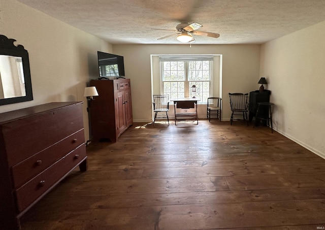 living area featuring dark wood finished floors, a textured ceiling, a ceiling fan, and baseboards