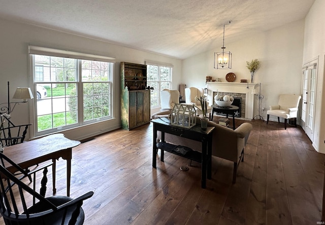 living area featuring lofted ceiling, a chandelier, dark wood-type flooring, and a fireplace