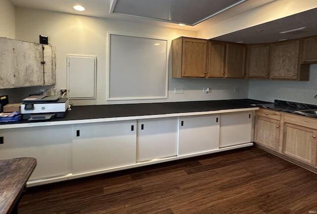 kitchen featuring dark countertops, dark wood-style floors, a sink, and recessed lighting