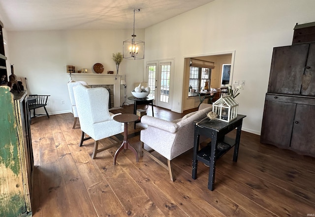 living room with a chandelier, french doors, baseboards, a brick fireplace, and dark wood-type flooring