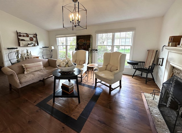 living area featuring a notable chandelier, vaulted ceiling, dark wood-style flooring, and a fireplace