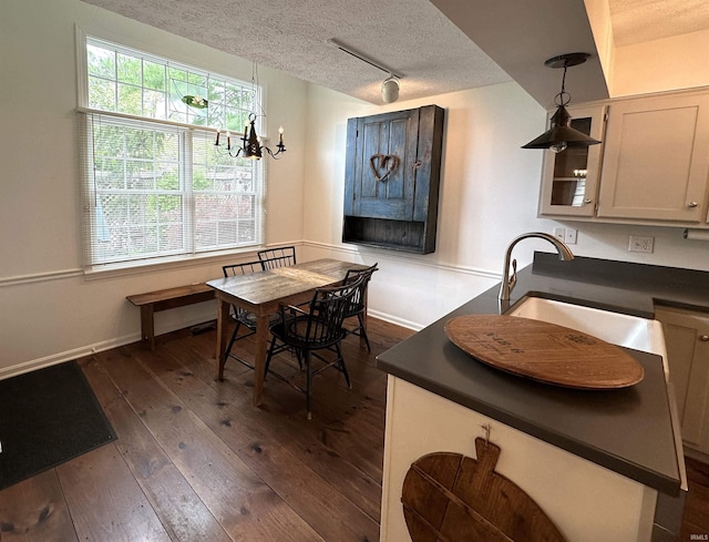dining area featuring a textured ceiling, dark wood finished floors, baseboards, a notable chandelier, and rail lighting
