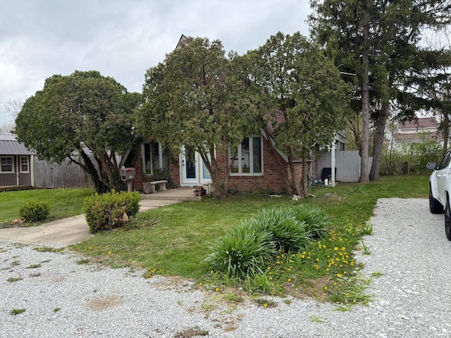 view of front of home with a front lawn, brick siding, and fence