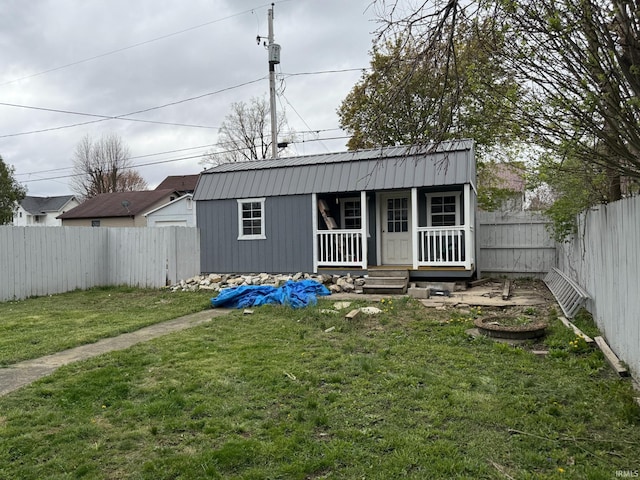 exterior space featuring a porch, a fenced backyard, a yard, and metal roof