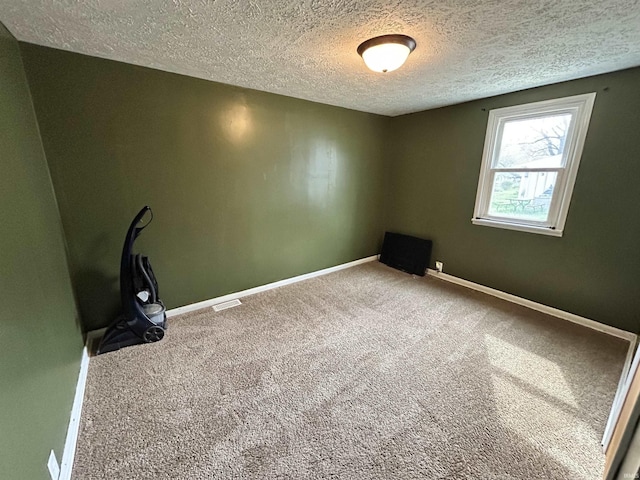 empty room with baseboards, carpet floors, visible vents, and a textured ceiling