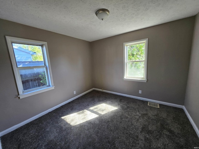 empty room featuring a textured ceiling, carpet floors, visible vents, and baseboards