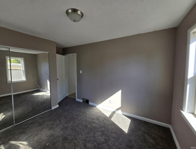 unfurnished bedroom featuring a closet, dark colored carpet, visible vents, and baseboards