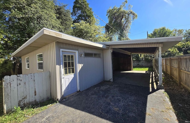 view of property exterior featuring fence, driveway, and an attached carport