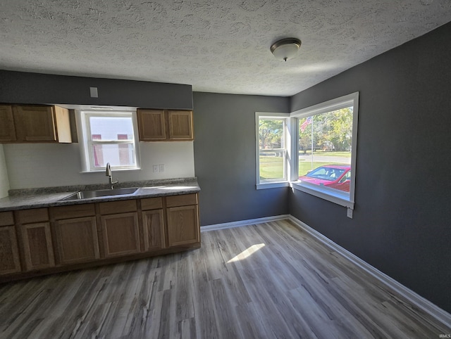 kitchen with a textured ceiling, a sink, and brown cabinets