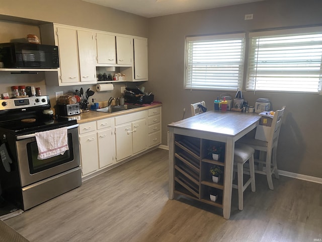 kitchen featuring black microwave, stainless steel range with electric stovetop, a sink, and light wood-type flooring