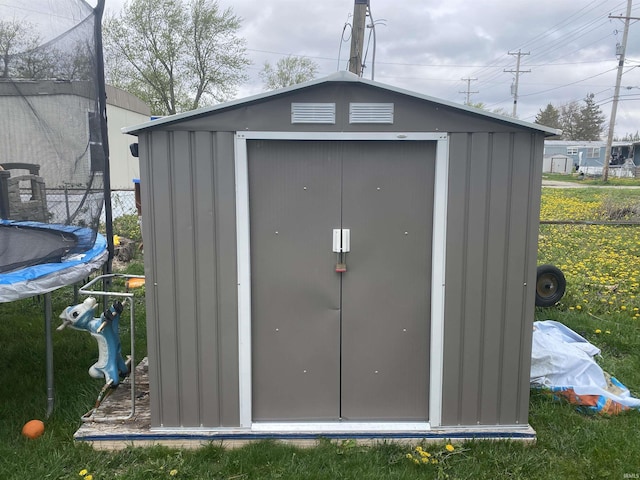 view of shed featuring fence and a trampoline