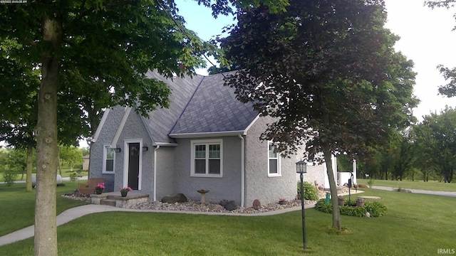 view of front of property with stucco siding, roof with shingles, and a front yard