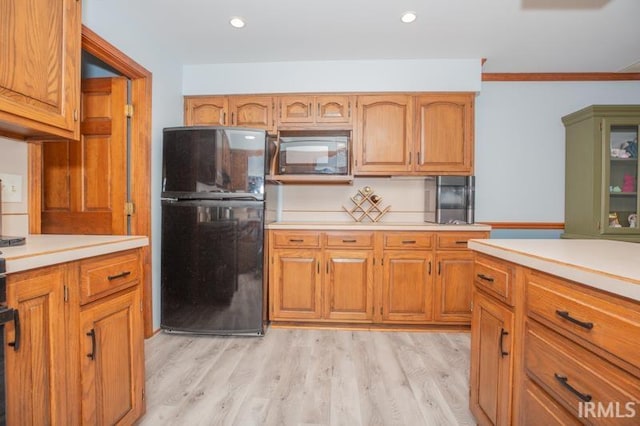 kitchen with black appliances, brown cabinets, light wood finished floors, and light countertops
