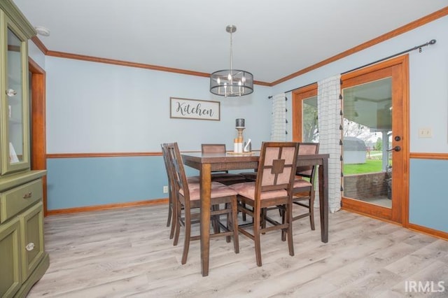 dining area featuring light wood-type flooring, baseboards, a notable chandelier, and crown molding