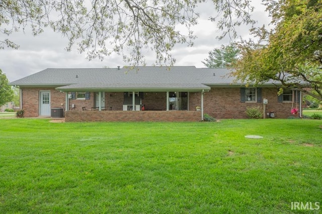 back of property with a lawn, brick siding, and central air condition unit
