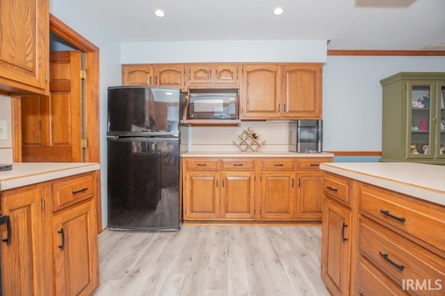 kitchen featuring light countertops, light wood-style flooring, and black appliances