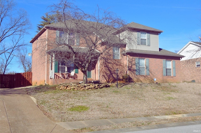 traditional-style house featuring fence, a porch, and a front lawn